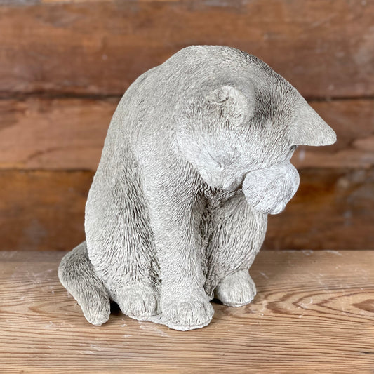 Närbild på betongfiguren Selma, katt som sitter och tvättar sig