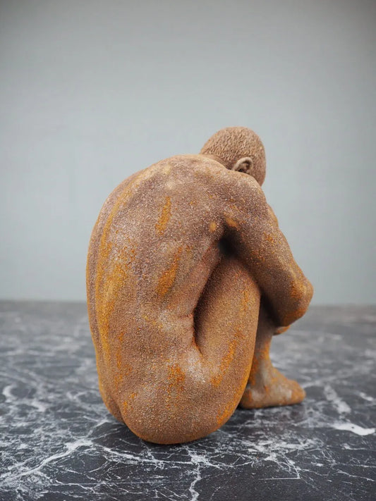 Sittande man skulptural dekorationsfigur snett framifrån