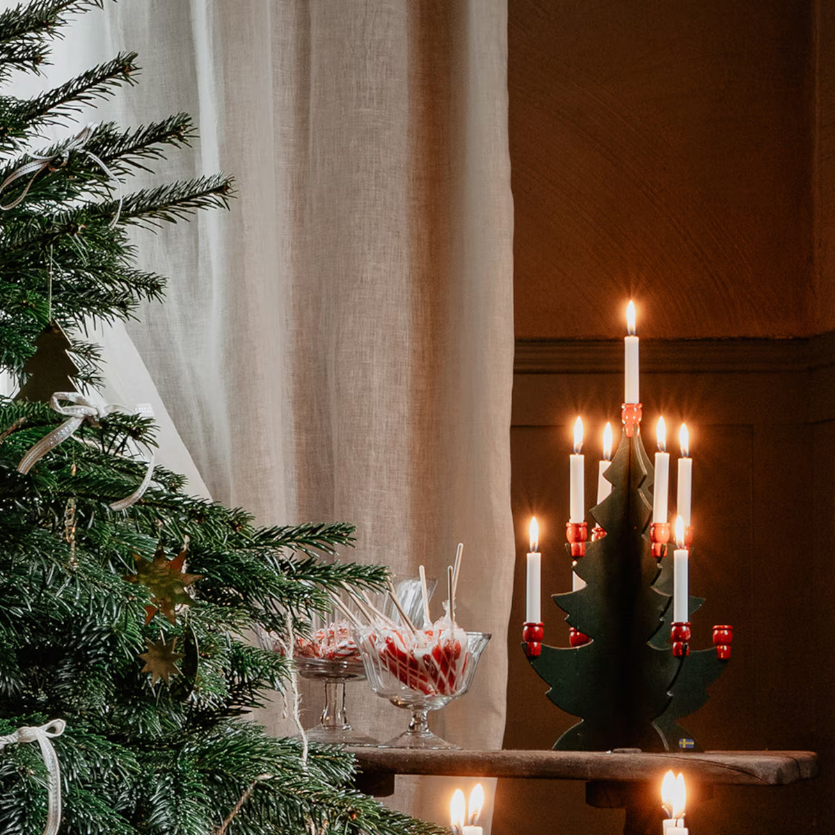 Grön och röd trägran med nio julgransljus i julmiljö