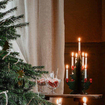 Grön och röd trägran med nio julgransljus i julmiljö