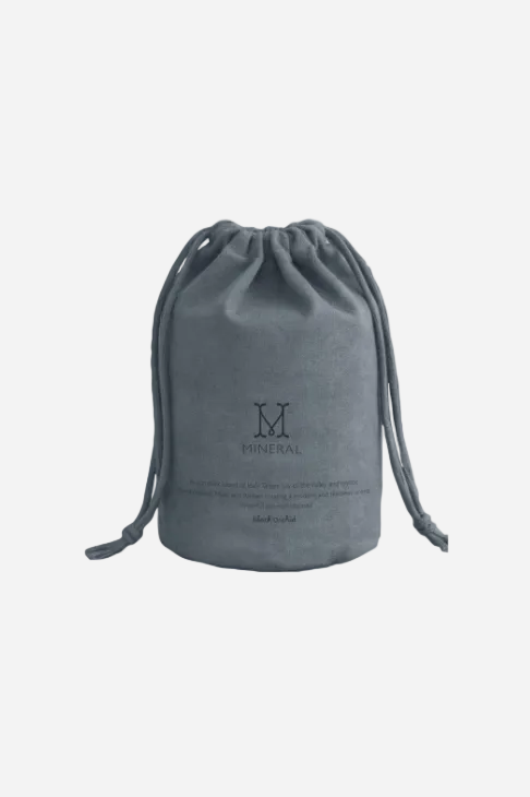 Grå tygpåse med Mineral-logotyp som medföljer doftljuset Black Orchid.