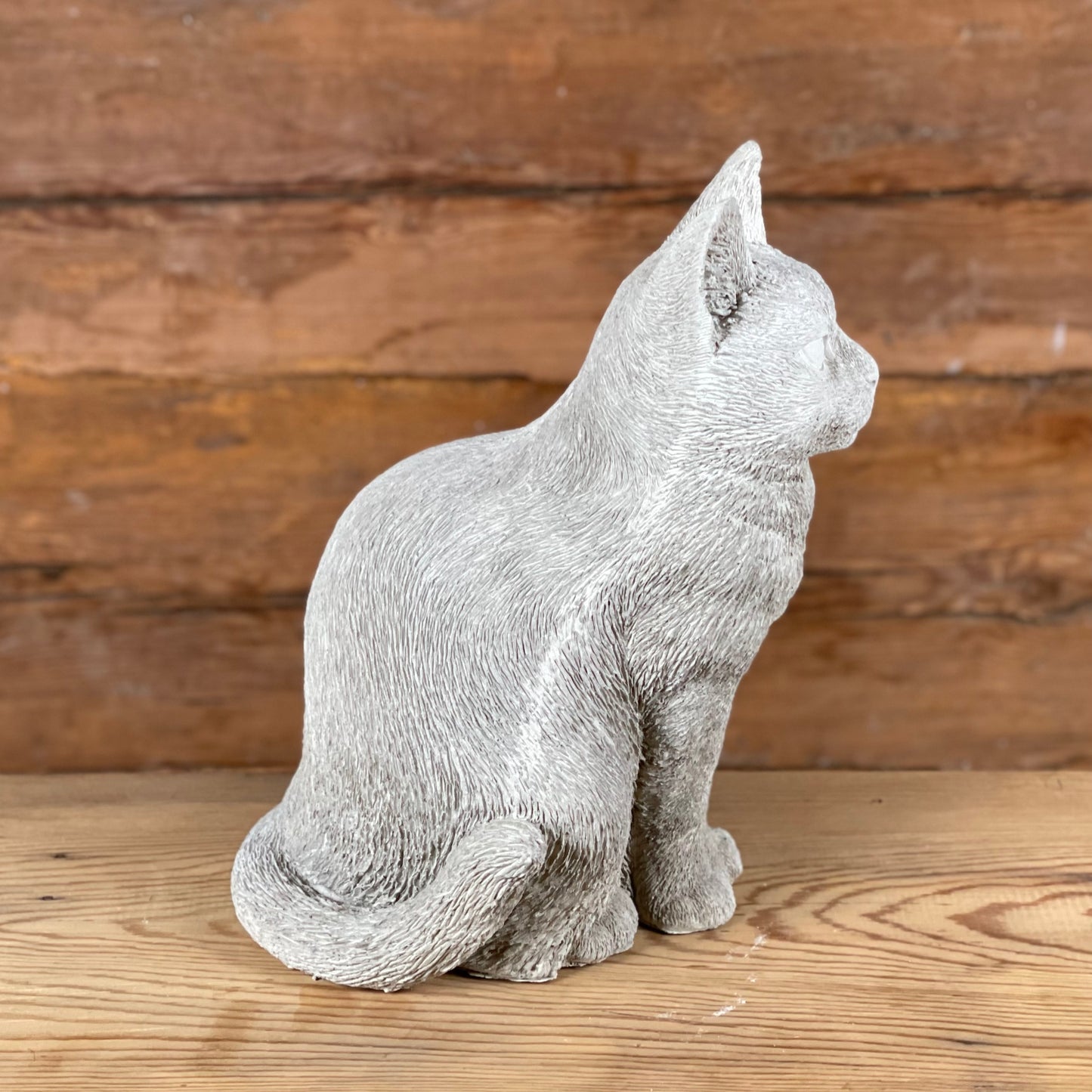 Katten Trisse – naturtrogen betongkatt sedd från sidan med böjd svans och mjuka former.