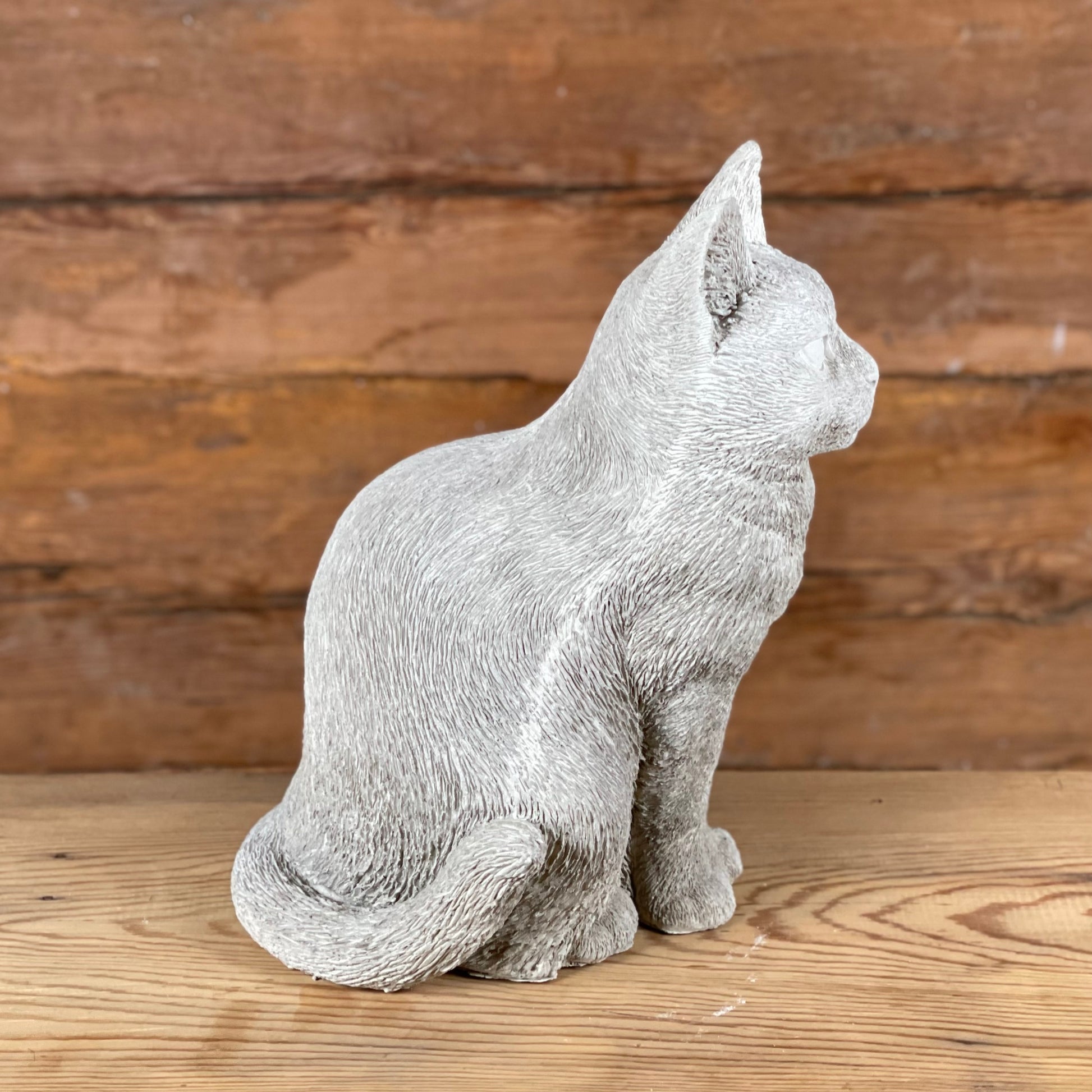 Katten Trisse – naturtrogen betongkatt sedd från sidan med böjd svans och mjuka former.