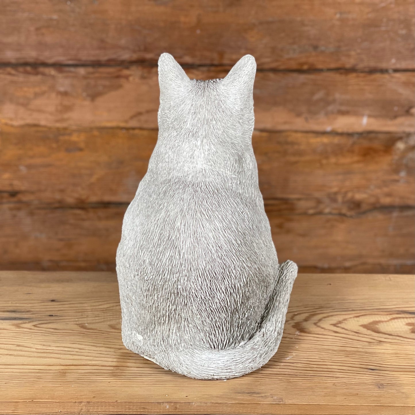 Katten Trisse – betongkatt sedd bakifrån med detaljerad svans och pälsstruktur.