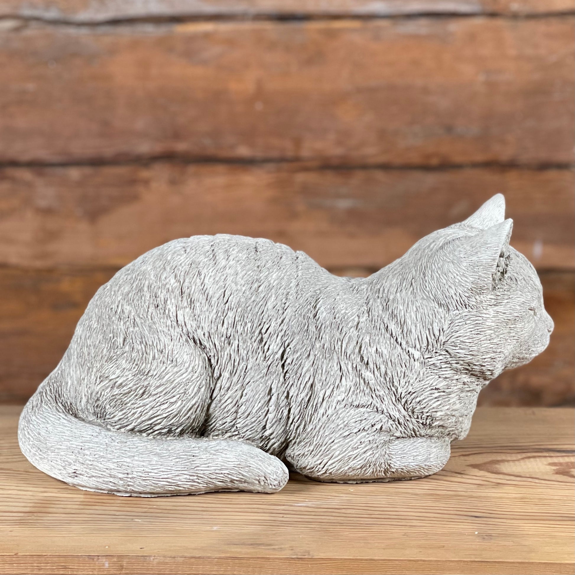 Betongfigur av liggande katt – Katten Måns, visad från sidan med markerad svans och pälsstruktur.