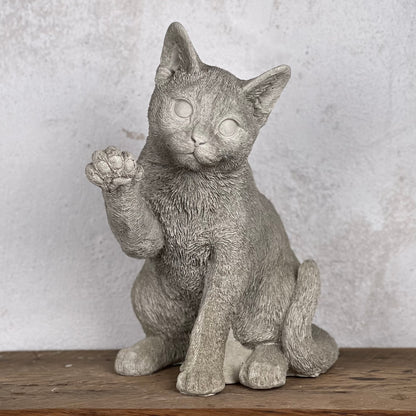 Betongkatt Ture som sitter och lyfter tassen i busig hälsning