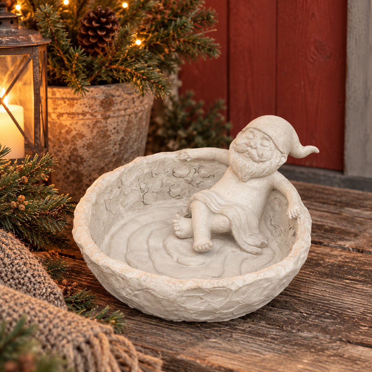 Badande tomte i betong sittande i en stor skål